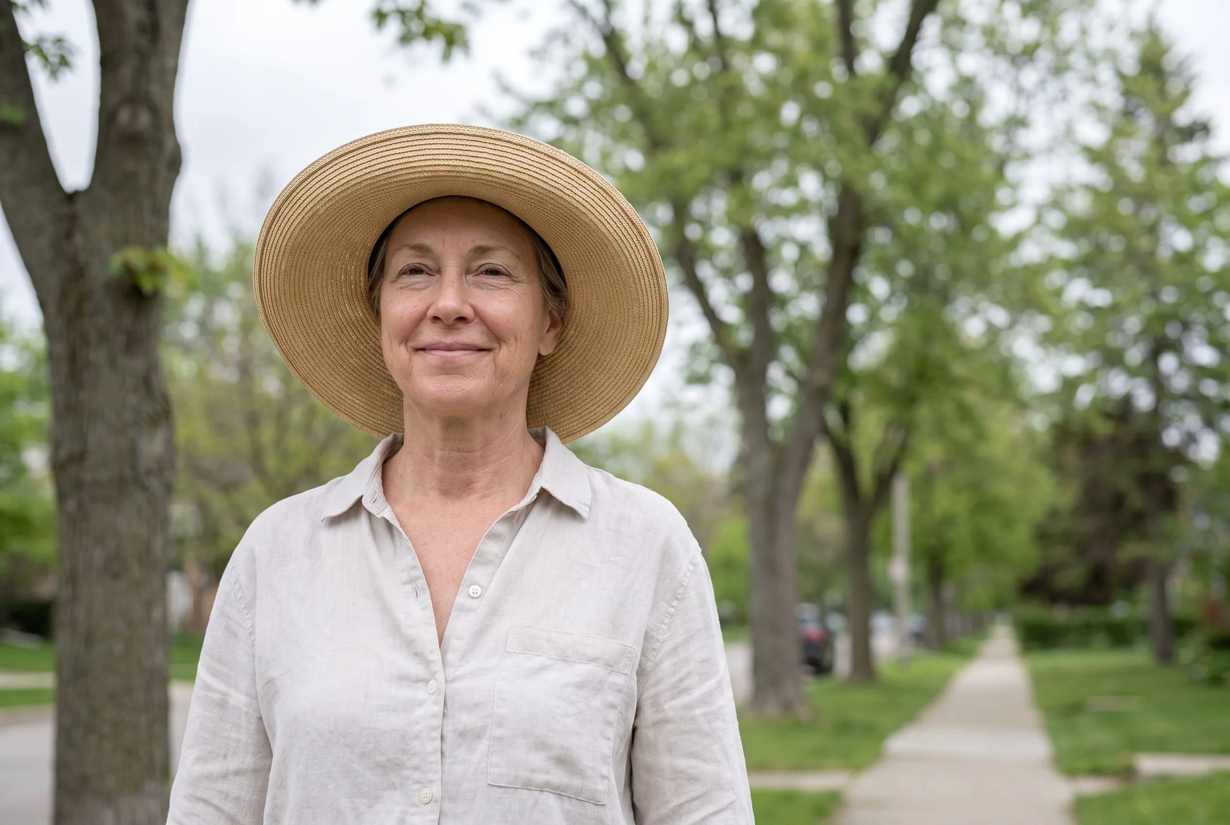 A woman in a wide-brim sun hat walking outdoors on an overcast day, when UV still reaches the skin.